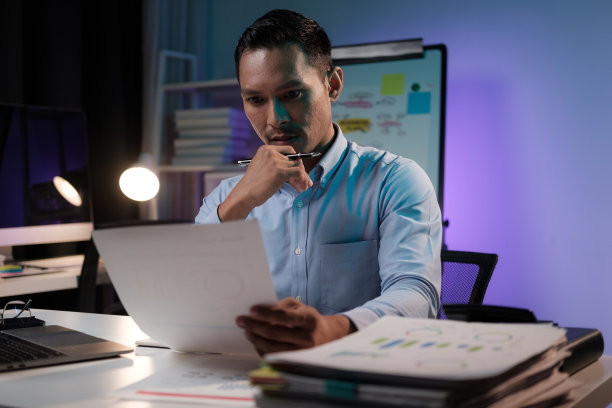 勤奋的亚洲商人在与团队的重要会议之前阅读文件，晚上在办公室工作。图片下载