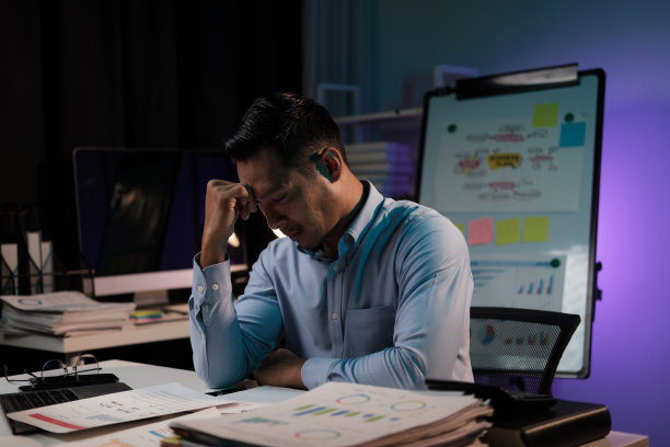 疲惫不堪的年轻亚洲商人在工作太多后感到沮丧和疲惫，独自在办公室里工作了一夜。图片下载