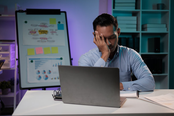 疲惫不堪的年轻亚洲商人在工作太多后感到沮丧和疲惫，独自在办公室里工作了一夜。图片下载