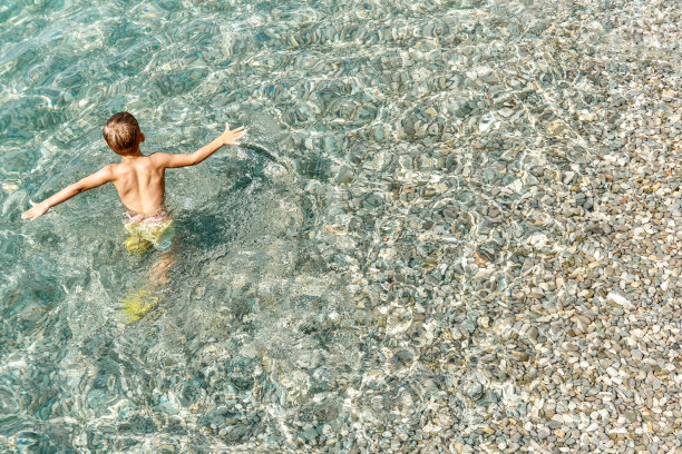 学龄前男孩喜欢在卵石滩探索海水图片下载