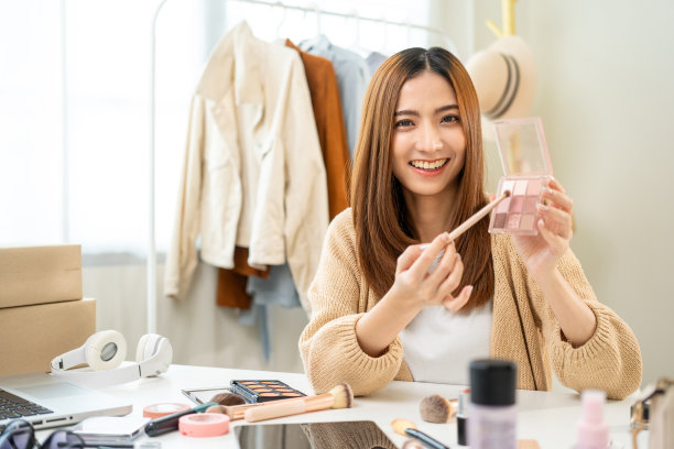 年轻美丽的亚洲女性视频博主直播化妆化妆教程内容与眼影。网红们在社交媒体上用各种化妆品录制视频，专业化妆图片下载