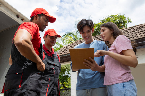一对年轻夫妇和两个从皮卡车上卸下箱子和家具的搬运工核对图片下载