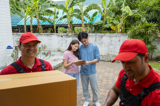 一对年轻夫妇和两个从皮卡车上卸下箱子和家具的搬运工核对图片下载