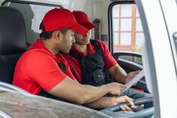 两名搬运工从一辆皮卡车上卸下箱子和家具。图片下载