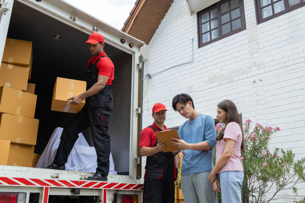一对年轻夫妇和两个从皮卡车上卸下箱子和家具的搬运工核对图片下载