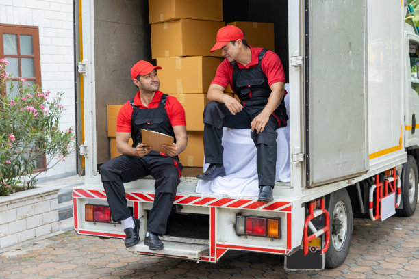 两名搬运工从一辆皮卡车上卸下箱子和家具。图片下载