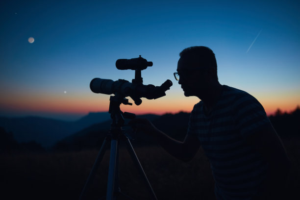 用望远镜观察星空和新月的天文学家。图片下载
