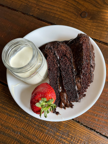 层叠，巧克力软糖蛋糕与奶油和草莓的玻璃罐，海绵片与层巧克力酱黄油糖霜在白色盘子，木纹背景，高架视图图片下载