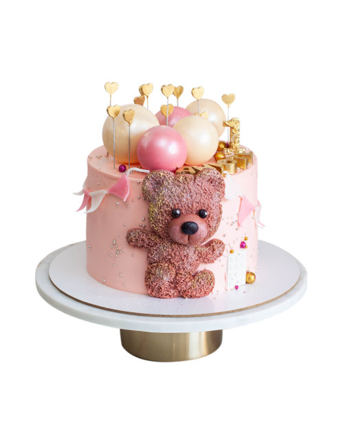 为女婴生日准备的粉色蛋糕，有巧克力球体，可爱的软糖泰迪熊玩具，金色的心和第一。隔离在白色背景上图片下载