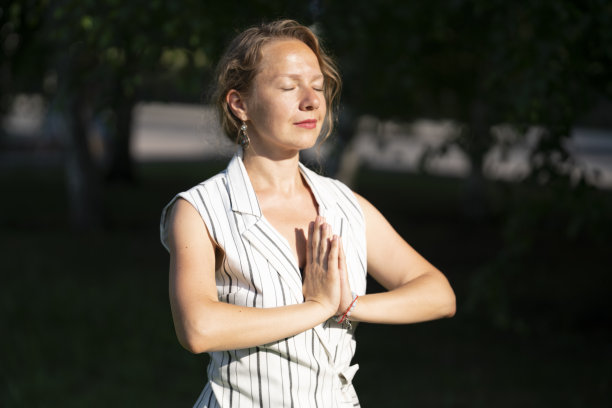 一个年轻的金发女子在午餐休息时坐在公园的草地上沉思。图片下载