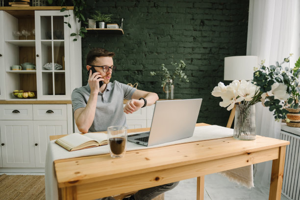 咖啡休息时间。认真的人工作，学习在线笔记本电脑在家庭办公室。交易cryptocurrency。交易员一边打电话一边看手表，投资者经纪人则在分析指数。自由图片下载