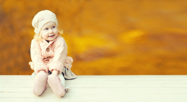 可爱的小男孩的肖像在温暖的阳光明媚的秋天公园户外穿着针织衣服在空模糊的黄叶背景图片下载