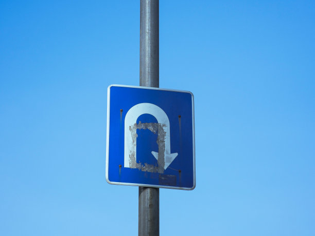 一个象征掉头的交通标志，上面印着印尼语警告，上面写着遵守交通规则。蓝色天空背景的交通标志照片图片下载