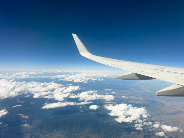 在阳光明媚的日子里，从飞机窗口看到山下山脉的白色翅膀。从飞机上可以看到沙漠景观和雪峰图片下载