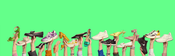 许多男人和女人的手拿着不同颜色和风格的鞋子在孤立的绿色背景与复制空间。网站或时尚博客的横幅。夏季鞋子促销活动。图片下载