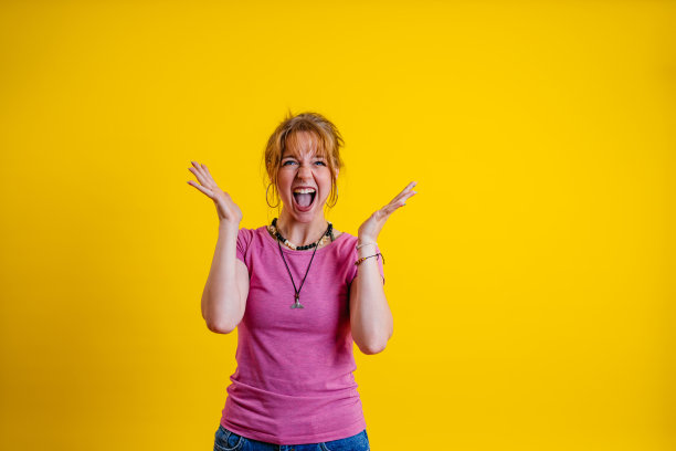 惊讶的年轻女子站在黄色背景下图片下载