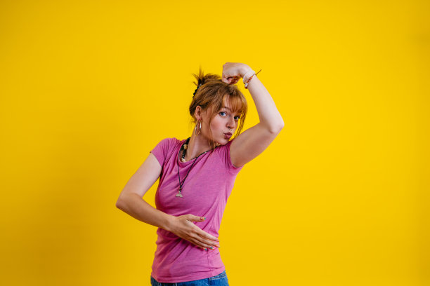 年轻女子在黄色背景下伸展肌肉图片下载