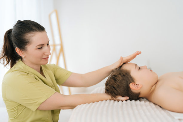 在儿科诊所接受整骨疗法或整脊疗法的五岁男孩的侧视图肖像。专业女性物理治疗师图片下载
