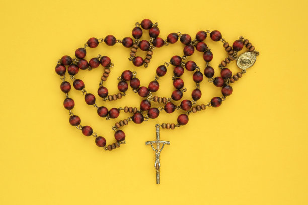 念珠木珠和十字架基督十字架在黄色的背景。图片下载
