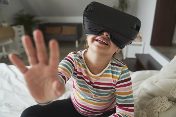小学生坐在床上戴着虚拟现实眼镜图片下载