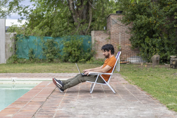 一个拉丁人在泳池里摆弄笔记本电脑图片下载