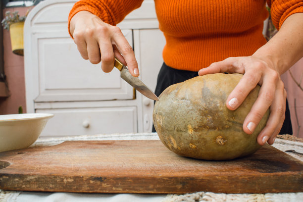 一个不知名的女人在用刀切南瓜，正面，复制空间。图片下载