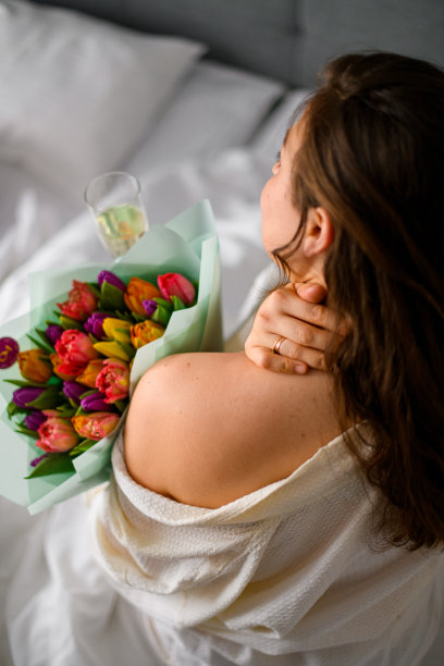 年轻的新娘在酒店公寓拿着一束彩色郁金香，俯视图图片下载