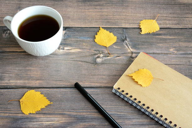 白色的咖啡杯放在木桌上，用黄色的桦树叶子复制空间图片下载