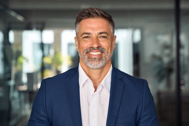 印度或拉丁自信成熟好看的中年领导，首席执行官，西装男商人在办公室背景的特写肖像。英俊的西班牙裔资深商人对着镜头微笑。图片下载