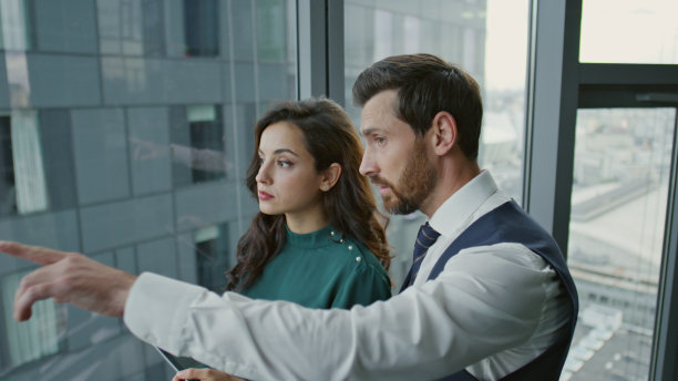 合作伙伴站在窗前讨论商业项目。图片下载