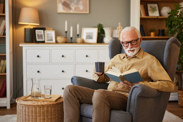 老人坐在家里的扶手椅上看书图片下载