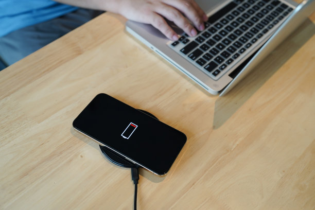 用桌上的无线充电装置给手机电池充电。智能手机在充电板上充电。手机附近无线充电器现代生活科技理念图片下载