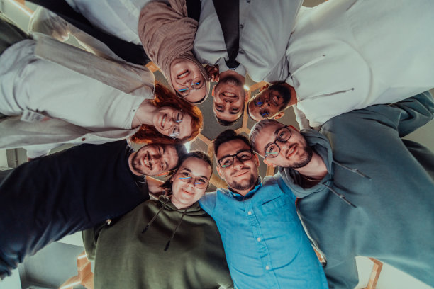 在现代办公室里，一群年轻的商务人士温暖地拥抱在一起，反映了他们在充满活力的工作场所中团结、合作和分享成功的精神。图片下载