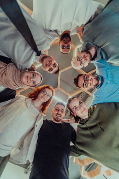 在现代办公室里，一群年轻的商务人士温暖地拥抱在一起，反映了他们在充满活力的工作场所中团结、合作和分享成功的精神。图片下载