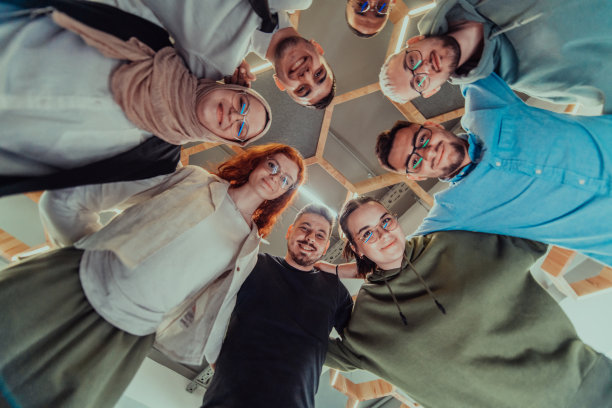 在现代办公室里，一群年轻的商务人士温暖地拥抱在一起，反映了他们在充满活力的工作场所中团结、合作和分享成功的精神。图片下载