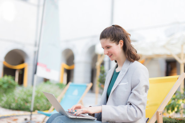 在公园里用笔记本电脑工作的年轻女子图片下载