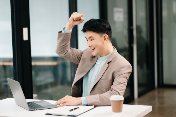 年轻的亚洲商人在办公室用笔记本电脑、平板电脑和在纸上做笔记。图片下载