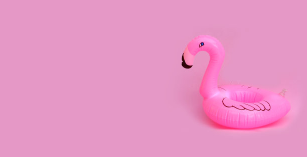 粉红色火烈鸟充气在粉红色的背景。夏季背景概念图片下载