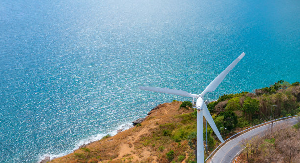 风力涡轮机在山和蓝色的海洋背景与文本的复制空间。图片下载