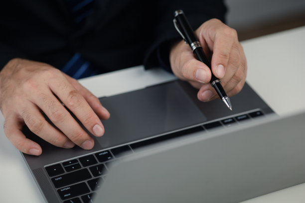 在笔记本电脑键盘上打字的人，在笔记本电脑上工作的商人，他正在给同事们打信息，并制作财务信息表来总结会议。图片下载