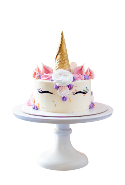 华丽的独角兽蛋糕，金色的华夫饼角，睫毛和奶油奶酪糖霜孤立在白色的背景图片下载