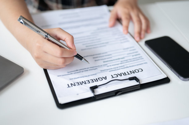 一个女人在桌子上签署合同的特写图片。图片下载