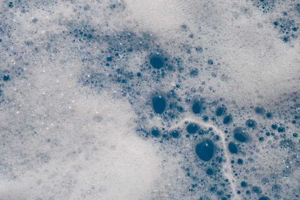 洗涤剂在水中起泡沫。蓝色背景，肥皂色图片下载