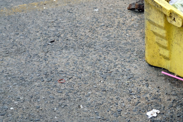 市场旁边的街道上一个旧的黄色塑料垃圾桶图片下载