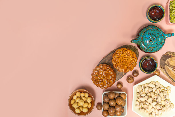 中秋节好吃的圆月饼。在甜蜜的粉红色背景上平铺着中秋节的食品和饮料。图片下载