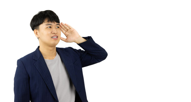 穿着夹克的年轻亚洲男子在白色背景上摆出手放在耳朵上的姿势。图片下载