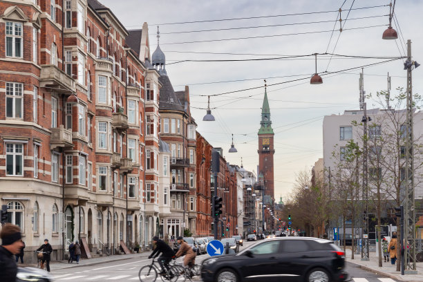 哥本哈根的城市景观，在这里你可以看到典型的建筑和过街的人。背景是一座教堂的塔楼。图片下载