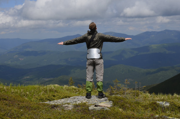 那个年轻人像鸟一样向两边张开双臂。山顶上的游客。图片下载