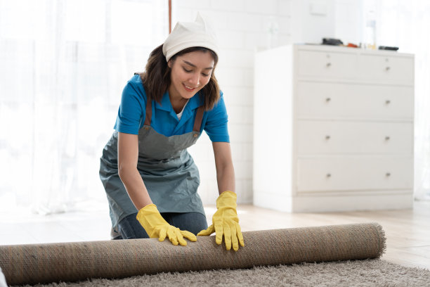 肖像亚洲妇女穿着工作服女仆打扫和卷起地毯在家里图片下载