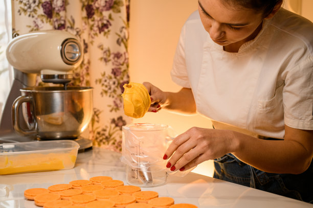 女糕点师在糖果袋里装满了新鲜制作的奶油，特写。模糊的背景图片下载